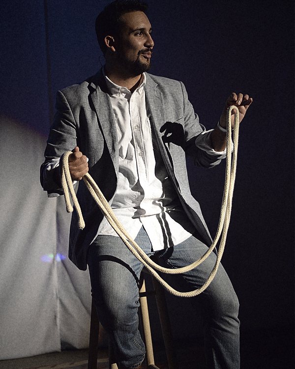 Javier Natera, mago para eventos en Cancún y la Riviera Maya, sentado en un banco con una cuerda durante su show