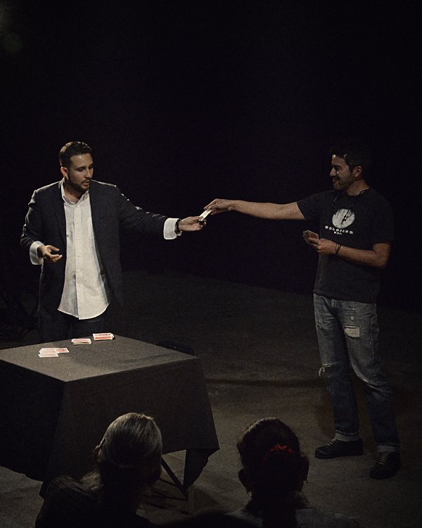 Javier Natera, mago y mentalista para posadas empresariales, entrega una carta a un participante del público bajo la luz del escenario